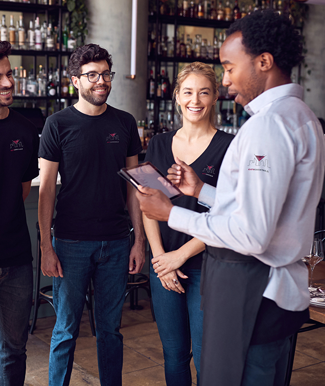 Male Restaurant Manager With Digital Tablet Giving Team Talk To Waiting Staff